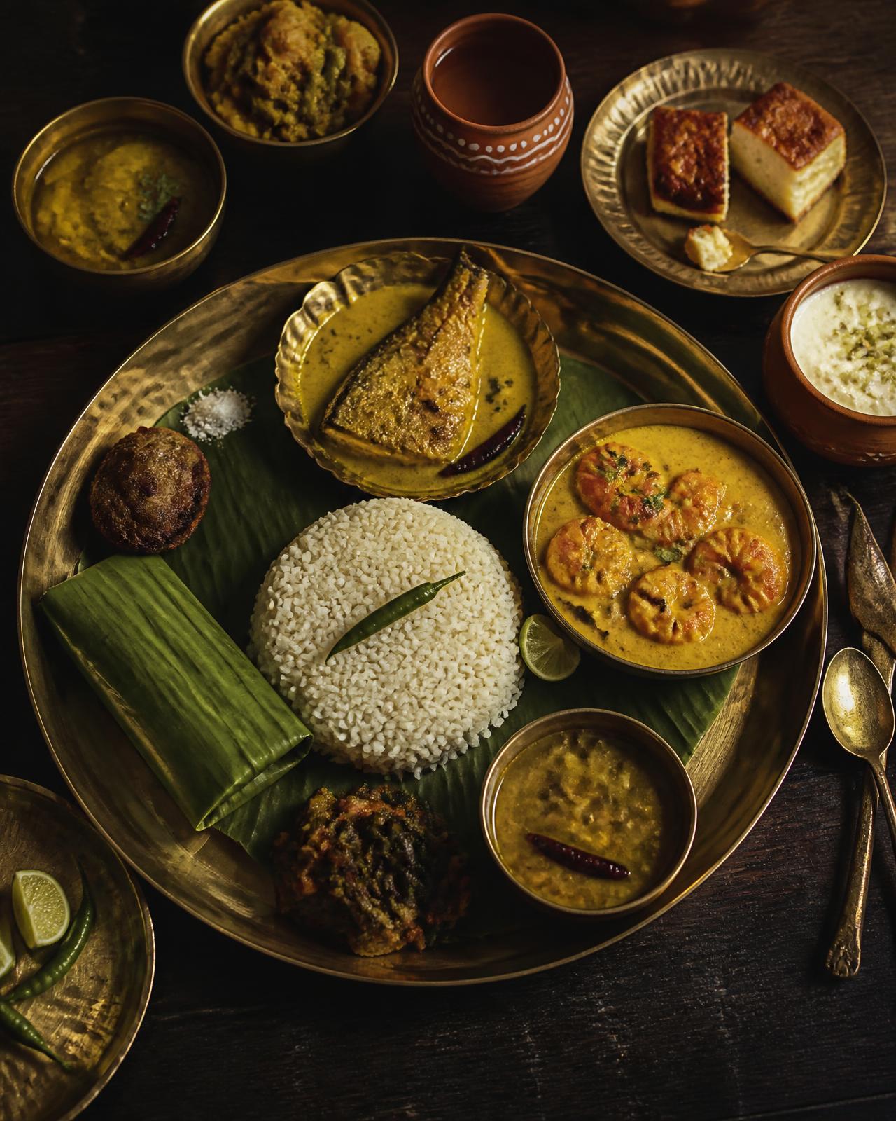 Odia and Bengali thali on a brass plate with mustard fish curry, prawns and rice